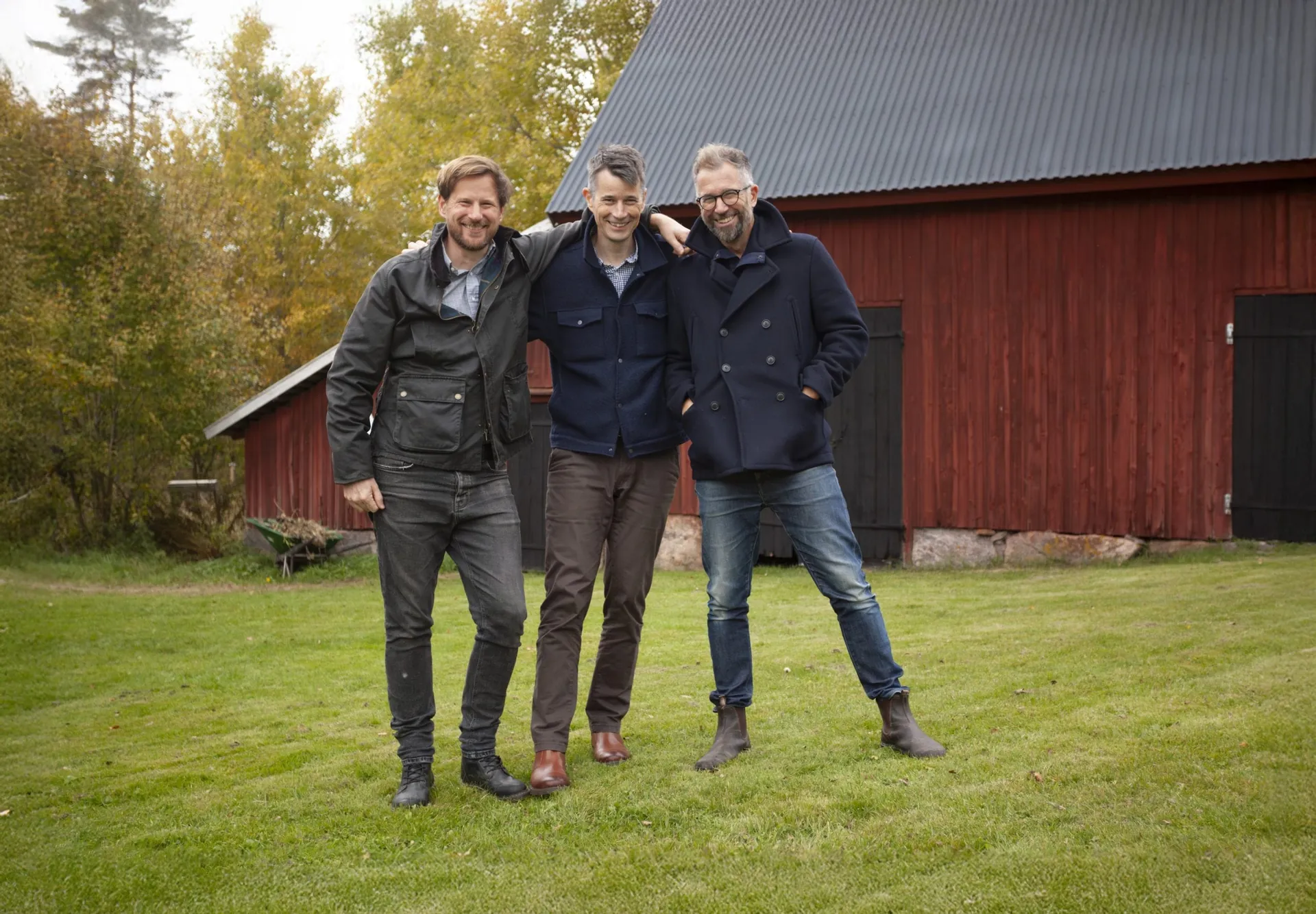 Mats, Ola and John Persson, the three brothers who co-founded Sirvoy, standing together in front of a red barn