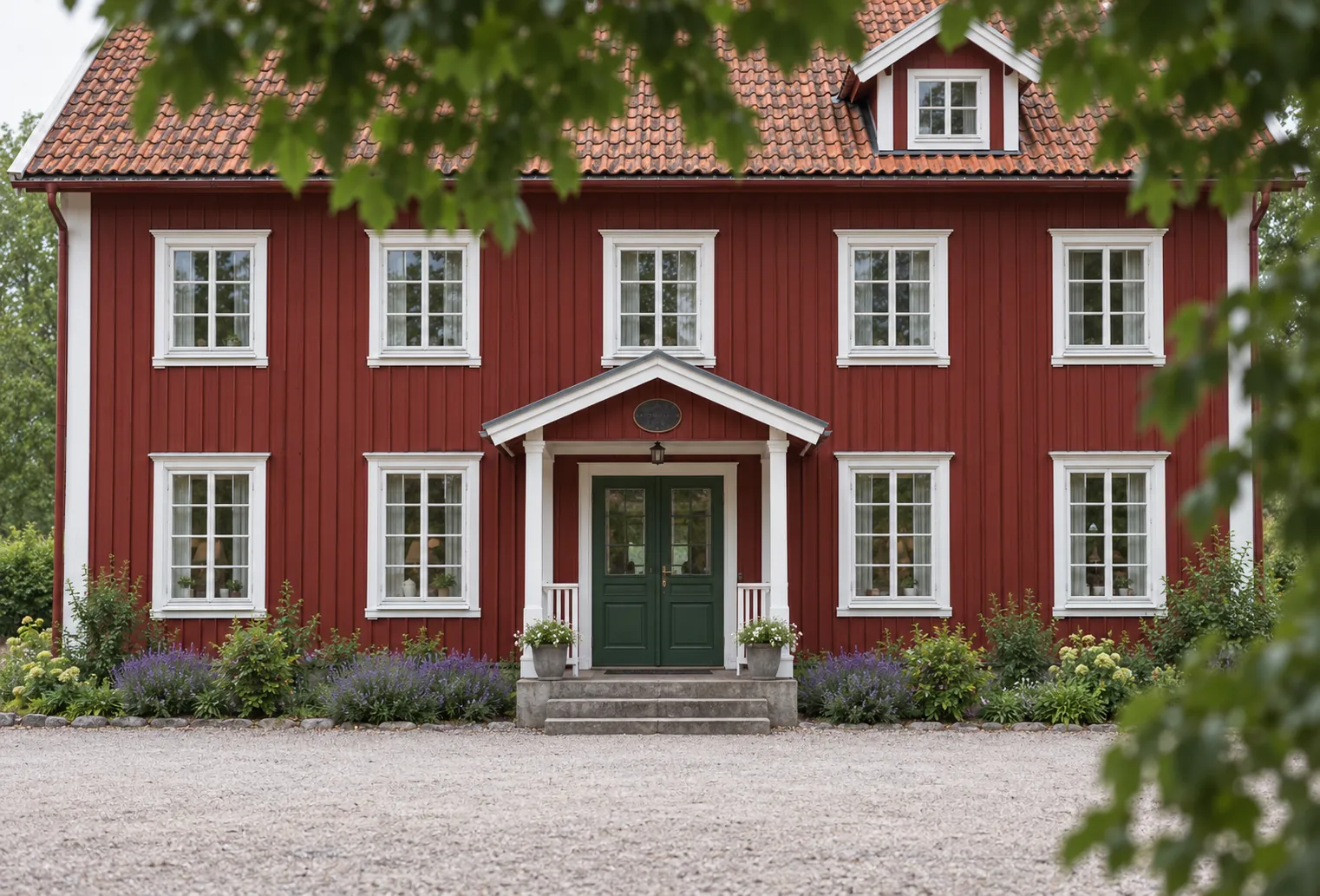 Rotes Holzhaus mit weißen Zierleisten und einer Kiesauffahrt